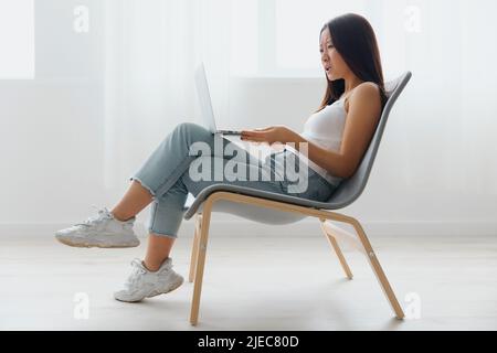 Verwirrt verärgert gebräunt schöne junge asiatische Frau schockiert durch die Operation Probleme mit Laptop zu Hause innen Wohnzimmer. Fernkommunikation Stockfoto