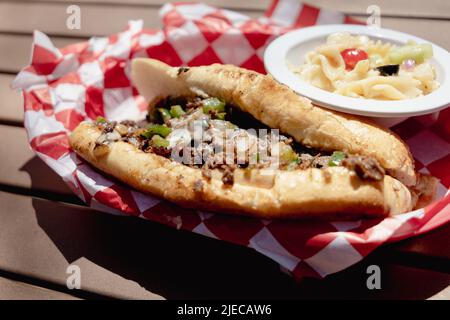 Ein Philly Cheesteak-Sandwich mit einer Beilage Nudelsalat in einem Retro-Korb Stockfoto