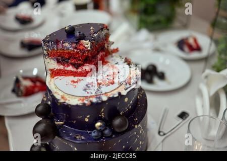 Schwarzer Stockkuchen auf dem dunkelschwarzen Hintergrund mit goldenen Sternen und Kugeln Dekoration auf der Oberseite. Luxuriöse Geburtstagstorte Stockfoto