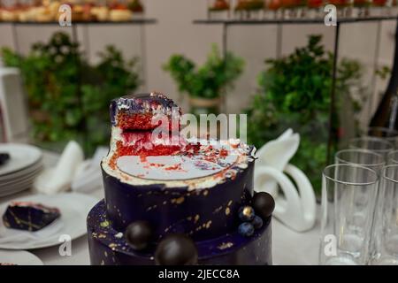 Schwarzer Stockkuchen auf dem dunkelschwarzen Hintergrund mit goldenen Sternen und Kugeln Dekoration auf der Oberseite. Luxuriöse Geburtstagstorte Stockfoto