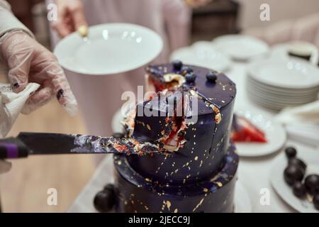 Schwarzer Stockkuchen auf dem dunkelschwarzen Hintergrund mit goldenen Sternen und Kugeln Dekoration auf der Oberseite. Luxuriöse Geburtstagstorte Stockfoto