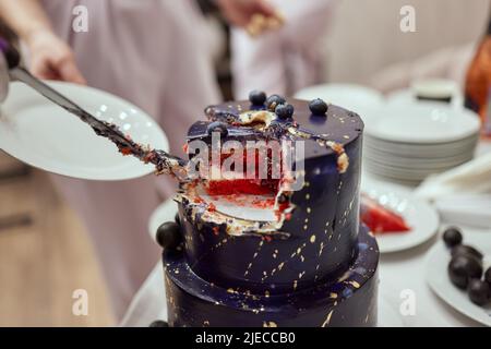 Schwarzer Stockkuchen auf dem dunkelschwarzen Hintergrund mit goldenen Sternen und Kugeln Dekoration auf der Oberseite. Luxuriöse Geburtstagstorte Stockfoto