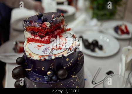 Schwarzer Stockkuchen auf dem dunkelschwarzen Hintergrund mit goldenen Sternen und Kugeln Dekoration auf der Oberseite. Luxuriöse Geburtstagstorte Stockfoto