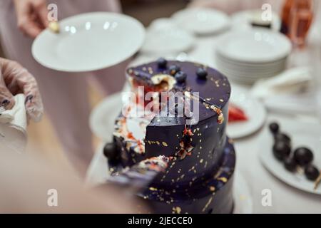 Schwarzer Stockkuchen auf dem dunkelschwarzen Hintergrund mit goldenen Sternen und Kugeln Dekoration auf der Oberseite. Luxuriöse Geburtstagstorte Stockfoto