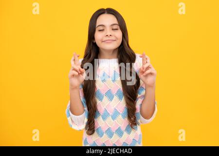 Porträt von entzückenden kleinen Teenager-Gitl stehen mit geschlossenen Augen und Kreuzungen Finger, Wunsch nach Viel Glück. Kindheitsträume und Hoffnungen. Stockfoto