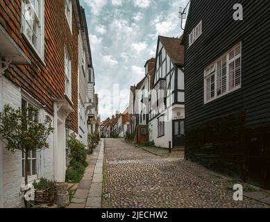 RYE, ENGLAND - 19.. APRIL 2022: Eine schmale gepflasterte srteet in Rye von Häusern begrenzt Stockfoto