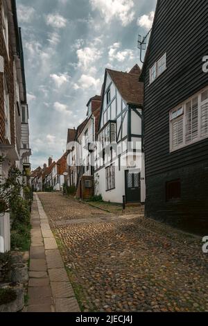 RYE, ENGLAND - 19.. APRIL 2022: Eine schmale gepflasterte srteet in Rye von Häusern begrenzt Stockfoto