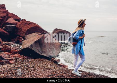 Frau, die auf der Insel Santorini, Griechenland, den Roten Strand und die Meereslandschaft genießt. Tourismus, Sommerreisen Stockfoto