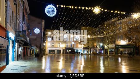 Zentrale Straße der französischen Stadt Monzelimar mit Weihnachtsschmuck in der Dämmerung Stockfoto