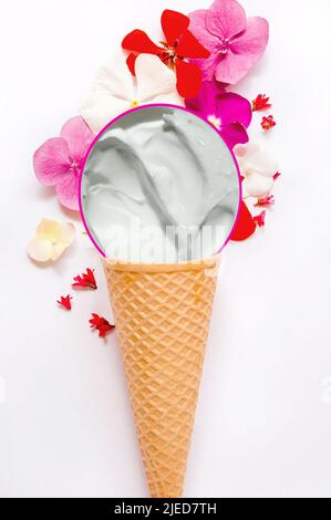 Feuchtigkeitsspendende, beruhigende Körpercreme mit Kräuteröl in einem Waffel-Eis-Kegel mit bunten Blumen Stockfoto