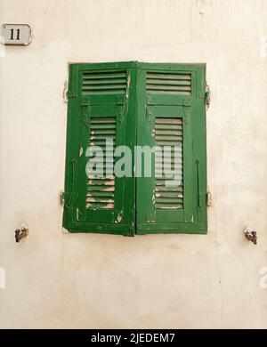 Lokale Architektur und Details von Häusern in der mittelalterlichen Altstadt von Ventimiglia in Italien, Ligurien in der Provinz Imperia. Grünes Fenster auf einem alten Stockfoto