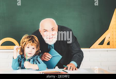 Lehrer Großvater mit Schüler auf der Rückseite des Klassenzimmers an der Grundschule. Lehrertag. Stockfoto