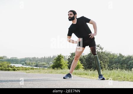 Fit Mann mit körperlicher Behinderung beim Aufwärmen Stretching vor dem Training Routine im Freien - Fokus auf Prothese Bein Stockfoto