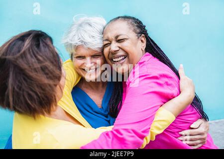 Glückliche, multirassische ältere Frauen, die Spaß daran haben, sich im Freien umarmen zu können - ein Lebensstil der älteren Gemeinschaft Stockfoto