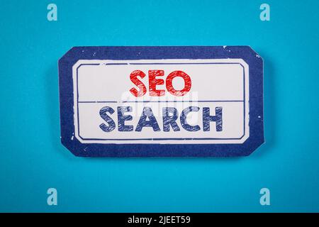 SEO, SUCHKONZEPT. Text auf einem Blatt Papier. Blauer strukturierter Hintergrund. Stockfoto