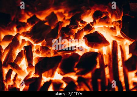 Abstrakter Hintergrund von glühenden Kohlen im Kamin mit Feuerflammen. Hintergrund brennender Flammen. Stockfoto