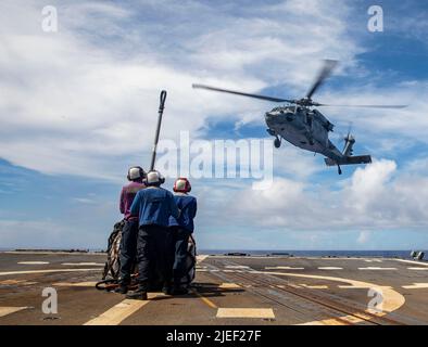 PHILIPPINISCHE SEEFAHRER (2. Juni 2022) an Bord des Lenkraketen-Zerstörers USS Dewey (DDG 105) der Arleigh Burke-Klasse bereiten sich darauf vor, während einer vertikalen Auffüllung mit dem Lenkraketen-Kreuzer Mobile Bay der Ticonderoga-Klasse Ladung an einen MH-60s Sea Hawk-Hubschrauber zu bringen, der den „Chargers“ des Helicopter Sea Combat Squadron (HSC) 14 zugewiesen wurde (CG 53). Die Abraham Lincoln Strike Group befindet sich im geplanten Einsatzgebiet der US-Flotte für 7., um die Interoperabilität durch Allianzen und Partnerschaften zu verbessern und gleichzeitig als reaktionsfähige Truppe zur Unterstützung einer freien und offenen Region im Indo-Pazifik-Raum zu dienen Stockfoto