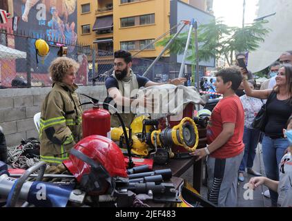 Beirut, Libanon. 26.. Juni 2022. Ein Feuerwehrmann fördert das Wissen über die Brandbekämpfung beim Life Beat Festival in der Hamra Street in Beirut, Libanon, 26. Juni 2022. Das Life Beat Festival, das auf die Förderung der öffentlichen Gesundheit und des Wohlbefindens ausgerichtet ist, fand am Sonntag in einer der beliebtesten Einkaufsstraßen in Beirut statt. Die Menschen genossen Gesundheitskonsultationen, Einkaufen, Essen, Trinken, Kunsthandwerk, Live-Auftritte während des Festivals. Quelle: Liu Zongya/Xinhua/Alamy Live News Stockfoto