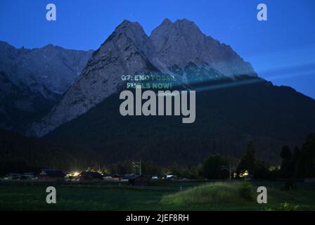 Garmisch Partenkirchen, Deutschland. 27.. Juni 2022. In den frühen Morgenstunden projiziert Greenpeace "G7: End Fossil Fuels Now" auf die Waxensteine. Deutschland ist Gastgeber des Gipfeltreffens der wirtschaftlich starken Demokratien G7 (26.-28. Juni). Quelle: Angelika Warmuth/dpa/Alamy Live News Stockfoto