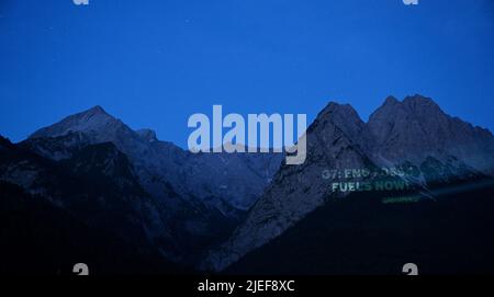 Garmisch Partenkirchen, Deutschland. 27.. Juni 2022. In den frühen Morgenstunden projiziert Greenpeace "G7: End Fossil Fuels Now" auf die Waxensteine. Deutschland ist Gastgeber des Gipfeltreffens der wirtschaftlich starken Demokratien G7 (26.-28. Juni). Quelle: Angelika Warmuth/dpa/Alamy Live News Stockfoto