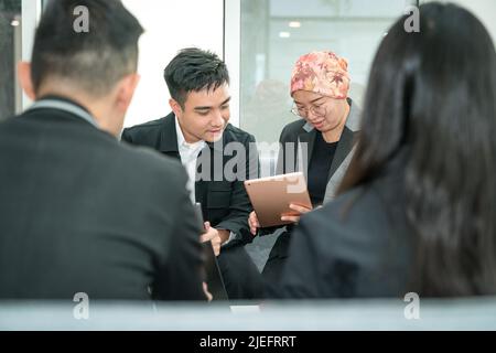 Kollegen aus dem Geschäftsbüro, die sich während eines Gesprächs mit einem digitalen Tablet-PC austauschen. Stockfoto