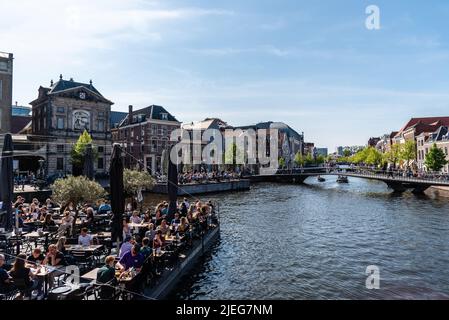 Leiden, Niederlande - 6. Mai 2022: Bootsterrasse voller Leute, die die Sonne, Essen und Getränke genießen. Das Café im Freien ist eine wichtige Freizeitbeschäftigung Stockfoto