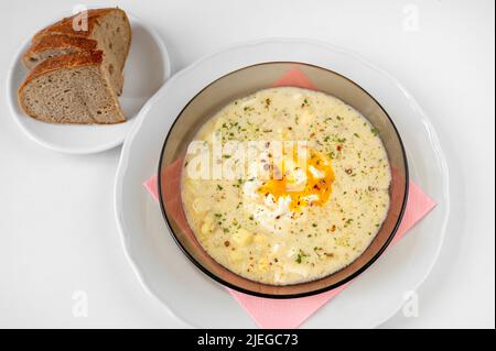 Kartoffelsuppe mit Ei und Dill auf dem Teller, Brotscheiben auf weißem Hintergrund. Traditionelle tschechische Suppe 'kulajda', süß-saure Suppe. Stockfoto