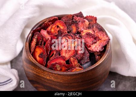 Getrocknete Erdbeerscheiben. Geschnittene getrocknete Erdbeeren auf dunklem Grund. Sonnengetrocknete Früchte. Nahaufnahme Stockfoto