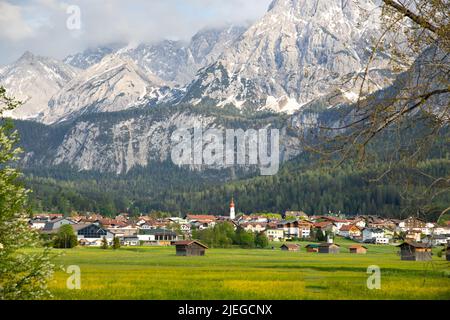 Kleines Dorf in Österreich mit den Alpen im Hintergrund. Stockfoto