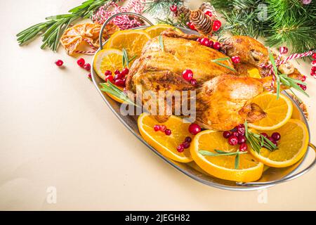 Traditionelles hausgemachtes Weihnachts-Huhn. Im Ofen gebackenes Huhn mit Orange, Preiselbeere Rosmarin und Gewürzen, auf beigem Hintergrund Copy Space Stockfoto