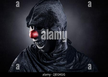 Scary Clown zeigt seine Zähne über dunklen nebligen Hintergrund Stockfoto