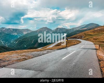 Serpentin in den Alpen. Eine leere Straße vor dem Hintergrund von Bergen und bewölktem Himmel. Europa Stockfoto