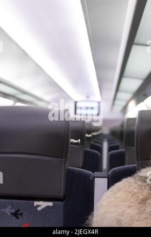 Eine leere Kabine des aeroexpress-Zuges ohne Passagiere. Weiche Sitze in einer Reihe mit Kopfstützen aus Leder. Öffentlicher Ort. Selektiver Fokus. Nahaufnahme Stockfoto