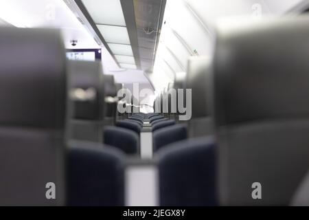 Eine leere Kabine des aeroexpress-Zuges ohne Passagiere. Weiche Sitze in einer Reihe mit Kopfstützen aus Leder. Öffentlicher Ort. Selektiver Fokus. Nahaufnahme Stockfoto