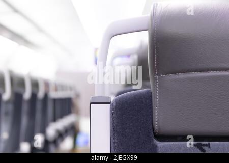 Eine leere Kabine des aeroexpress-Zuges ohne Passagiere. Weiche Sitze in einer Reihe mit Kopfstützen aus Leder. Öffentlicher Ort. Selektiver Fokus. Nahaufnahme Stockfoto