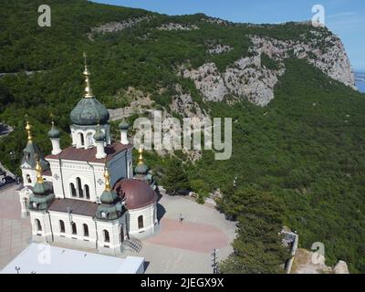 Luftaufnahme der Kirche von Foros und der Bergstraße durch den Frühlingswald. Beliebte Touristenattraktion in der Nähe von Jalta auf der Krim. Draufsicht Kirche des Heiligen Stockfoto