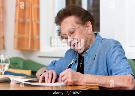 Eine alte Frau schreibt einen Vertrag, Senioren, Stockfoto