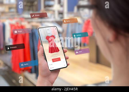 Shopping mit Smartphone und Augmented Reality App im Boutique-Konzept. Versuchen Sie auf die neuesten Kleidung in verschiedenen Größen und Farben. Frau hält Stockfoto