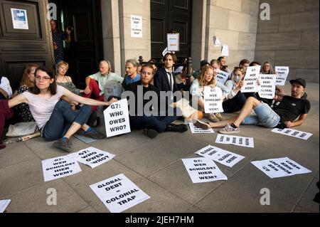 Berlin, Deutschland. 27.. Juni 2022. Aktivisten sitzen vor dem Finanzministerium und demonstrieren für globalen Schuldenerlass und Klimagerechtigkeit. Quelle: Christophe Gateau/dpa/Alamy Live News Stockfoto