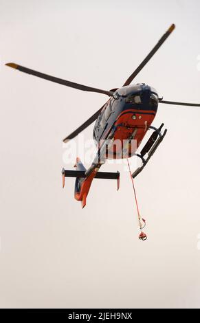 Cornwall, England, Großbritannien. 2022. Ein moderner Hubschrauber im Flug mit überdachtem Heckrotor und roten und blauen Farben. Stockfoto