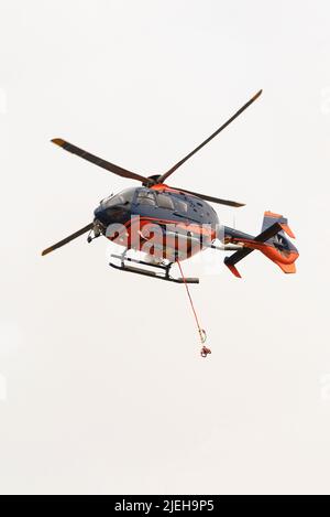 Cornwall, England, Großbritannien. 2022. Ein moderner Hubschrauber im Flug mit überdachtem Heckrotor und roten und blauen Farben. Stockfoto