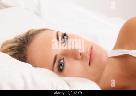 Eine junge Frau liegt wach in Bett. Schlafflos und nachdenklich. Stockfoto