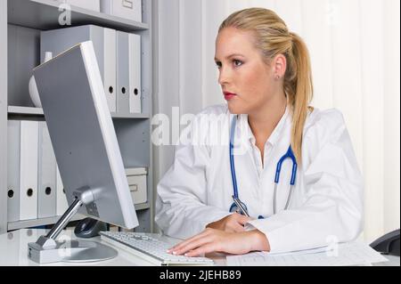 Eine junge Ärztin mit Stethoskop in ihrer Arztpraxis. Stockfoto