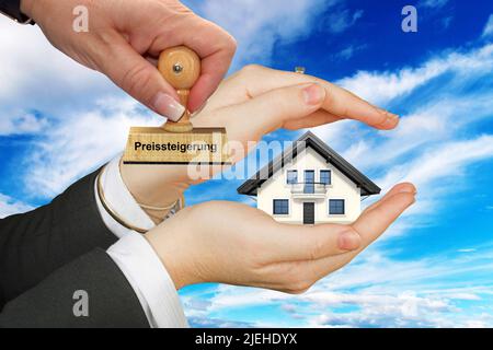 Immobilien werden teurer, schützende Hand mit Einfamilienhaus, Freisteller, weisser Hintergrund, Wolkenhimmel, Frauenhand, Preissteigerung, Stockfoto