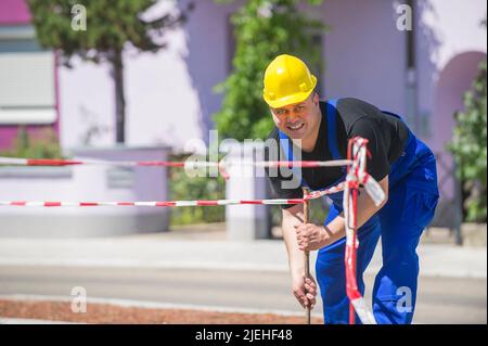 Ein Arbeiter überwacht die Baustellenabsperrung, Mann, 35, 40, Jahre, gelber Schutzhelm, Stockfoto