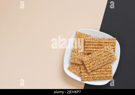 Sesambalken mit Erdnüssen in Platte auf zweifarbigem Hintergrund, Draufsicht mit Kopierraum Stockfoto