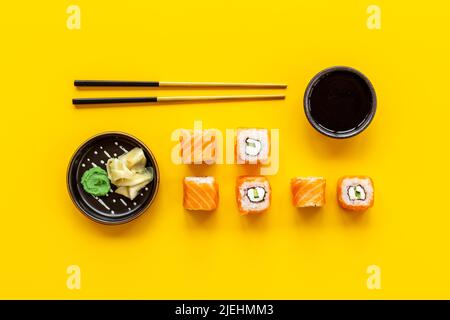 Lachs-Sushi-Brötchen mit Essstäbchen auf dem Tisch, Draufsicht Stockfoto