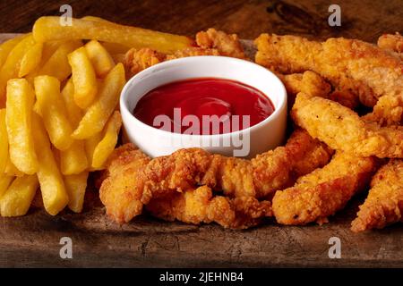 Hähnchenbrötchen, paniert und gebraten, mit einem roten Dip und Pommes frites, eine Nahaufnahme Stockfoto