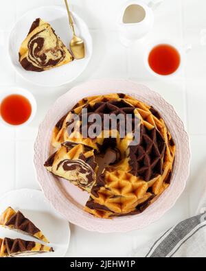 Marmorgebündete Torte, Pound Cake oder Butterkuchen in Scheiben geschnitten, serviert mit Tee. Auf Weißem Tisch Stockfoto