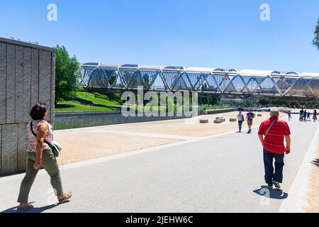 Madrid Rio Park. Blick auf den Madrider Río-Park neben dem Fluss Manzanares und die grüne Vegetation um ihn herum. Straßen mit Brücken und Fußgängerbrücken. Stockfoto